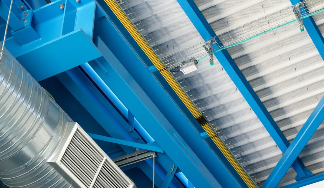 Spiral ductwork and an air handling unit below the steel ceiling of an industrial plant